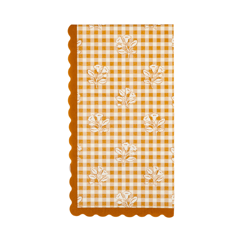 Fall gingham dinner napkin in orange and cream block-print with scattered floral accents and an orange wavy edge, overhead flat-lay.