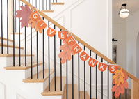 Give Thanks felt banner styled as Thanksgiving autumn decor across a modern home staircase railing accented with fall leaves.