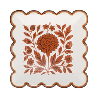 Cream scalloped paper plate with an orange marigold floral, brown edge, and gold foil accents, front view.