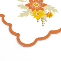 Corner detail of the rust scalloped edge on a fall floral paper napkin