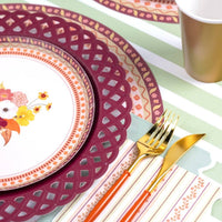 Fall place setting with the burgundy plate, floral plate, gold flatware, and a plaid runner.