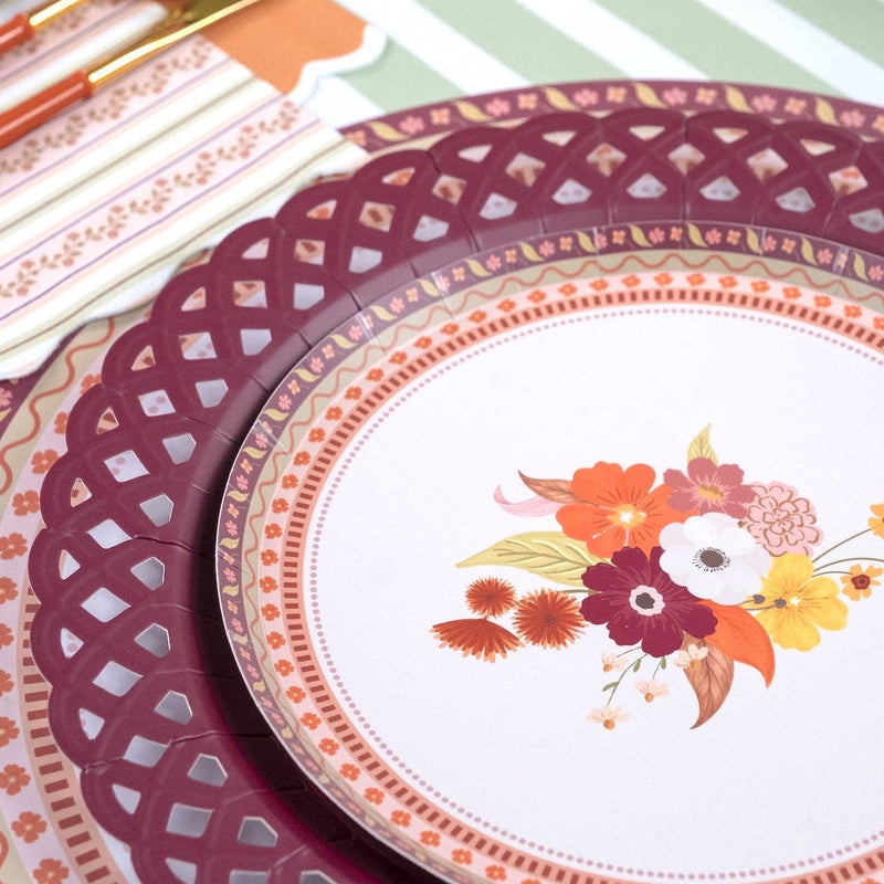 Styled fall place setting showing the floral dessert plate layered on a burgundy basketweave charger with a burgundy napkin and gingham runner.