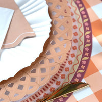 Fall place setting close-up showing the floral placemat under a burgundy lattice charger with a striped runner.
