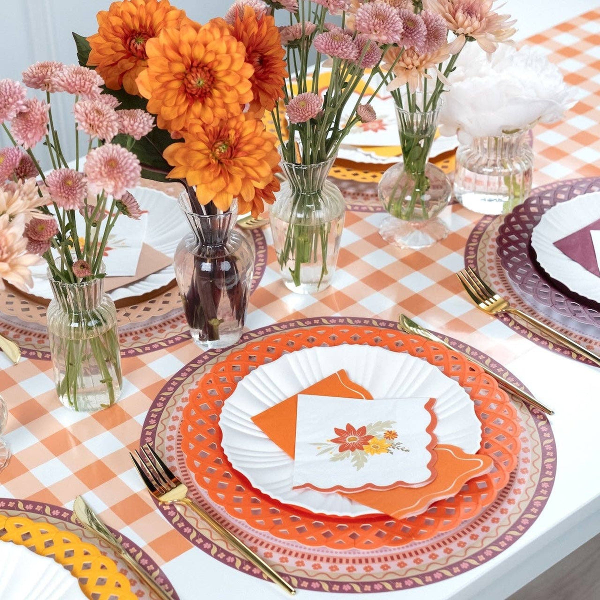 Styled fall place setting showing the floral placemat under a wordmark plate with orange florals and a black cat figure.
