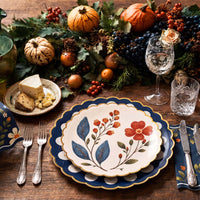 Fall dinner place setting with a wildflower plate layered on a navy doily plate beside cheese and a pumpkin centerpiece
