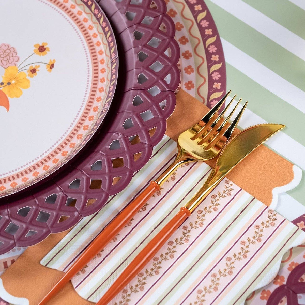 Styled fall place setting showing the striped napkin with a floral plate on a burgundy basketweave charger over a striped runner.