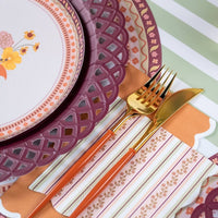 Styled fall place setting showing the striped napkin with a floral plate on a burgundy basketweave charger over a striped runner.