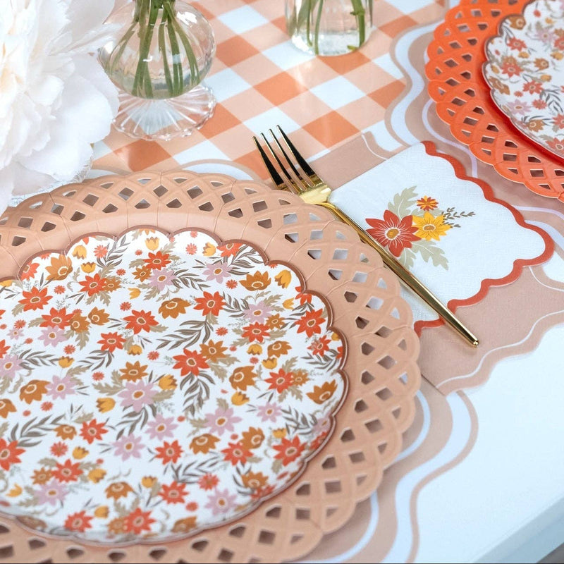 Styled fall place setting showing the tan napkin with floral plates on a scalloped charger over a gingham runner.