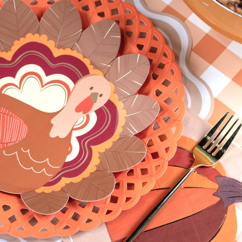 Styled fall place setting showing the turkey plate layered on an orange lattice charger with a burgundy napkin and gingham runner.