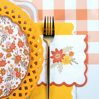 Fall place setting close-up showing the yellow basketweave charger under a floral plate with a striped runner.