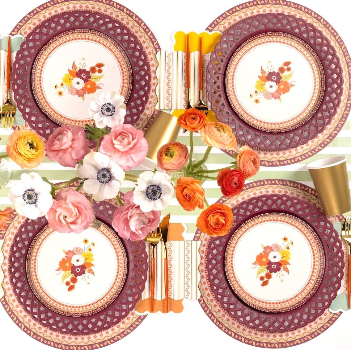 Overhead fall table with multiple burgundy basketweave plates, floral salad plates, gold flatware, and autumn florals.