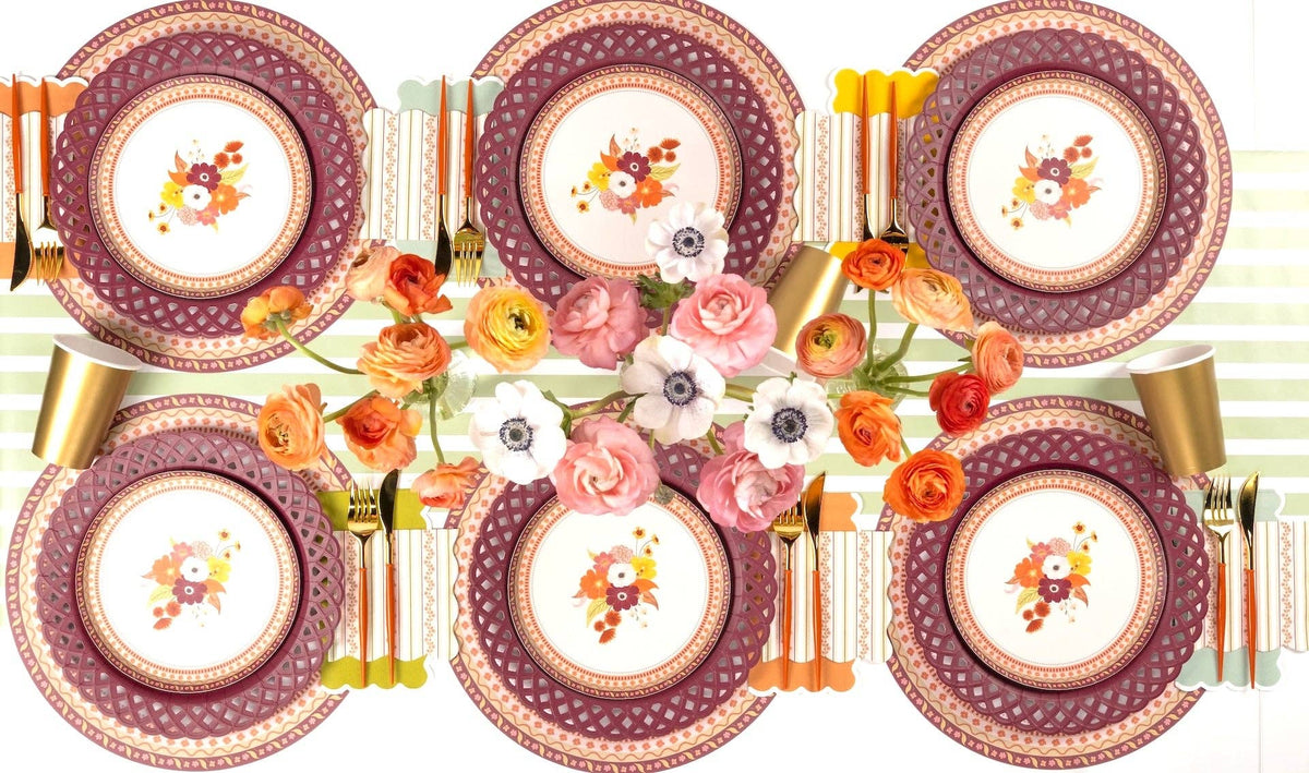 Overhead fall table showing the floral dessert plates with burgundy chargers, gold flatware, orange florals, and a striped runner.