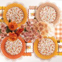 Overhead fall table flat lay showing the tan napkins with floral placemats, floral plates, and orange florals.
