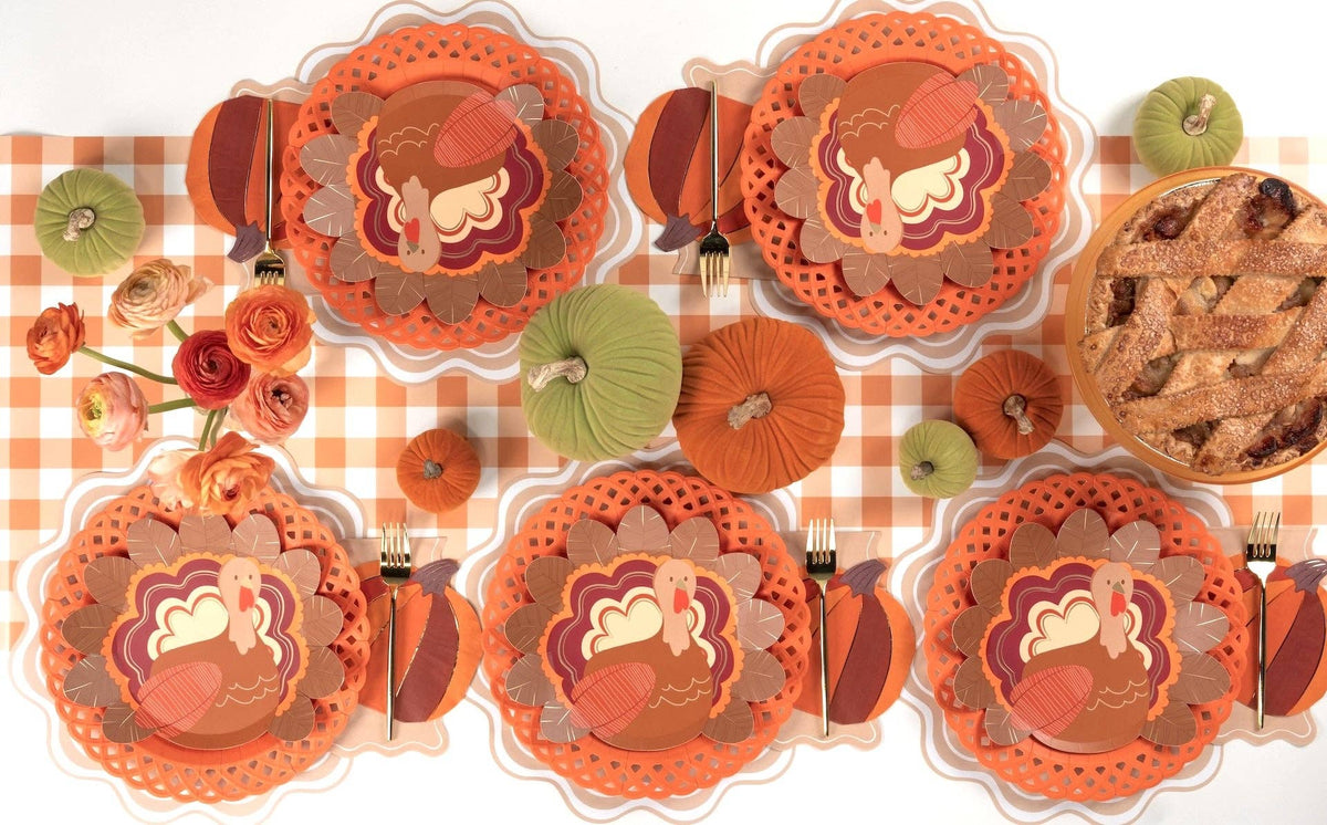 Overhead fall table showing turkey shaped plates with floral plates, orange chargers, cookies, and autumn florals.