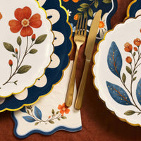 Fall place settings with wildflower plates, a navy doily plate, gold flatware, and a wavy edge napkin