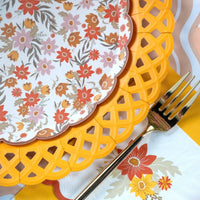 Overhead fall table flat lay showing yellow basketweave plates with floral plates, orange cups, and autumn accents.