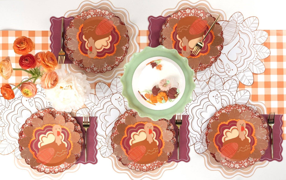 Overhead fall tablescape showing the burgundy napkins layered with pumpkin and turkey plates, a green plate, and fall florals.