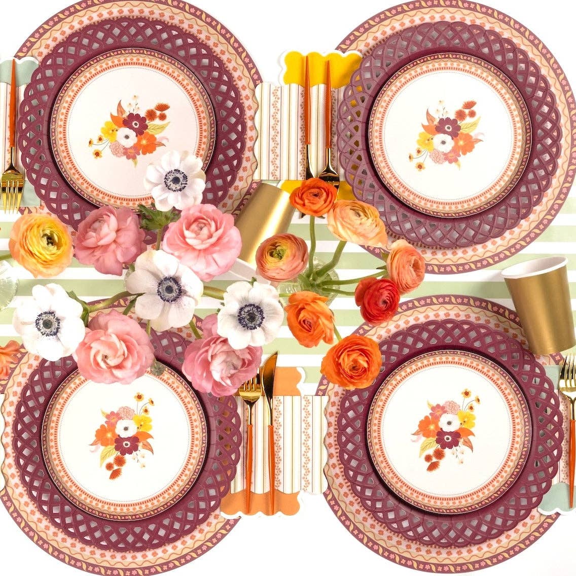 Overhead fall tablescape showing multiple floral dessert plates on burgundy chargers with pink and orange florals and gold flatware.