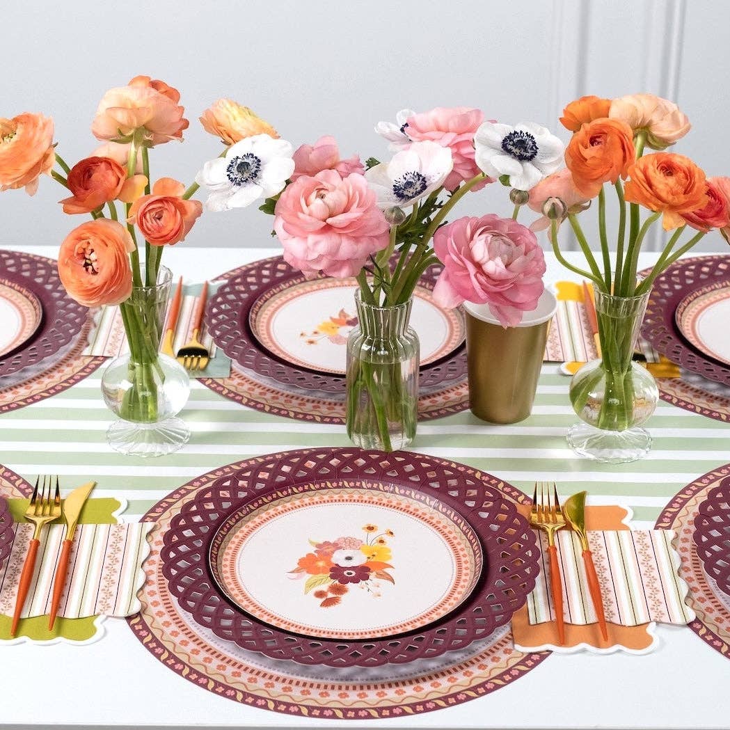 Styled fall tablescape showing the floral dessert plates on burgundy chargers with fresh flowers in vases and a striped runner.