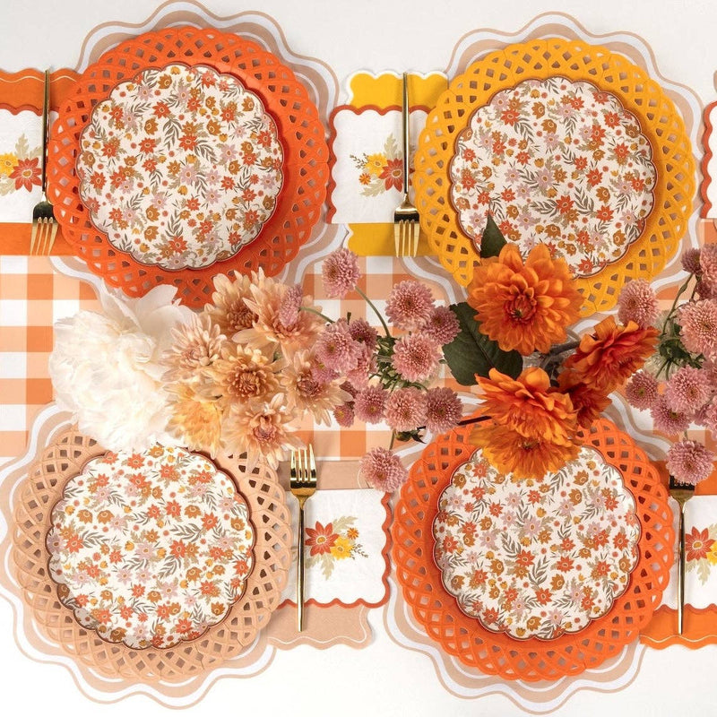 Overhead fall tablescape showing orange basketweave plates layered with floral salad plates, gold flatware, and autumn florals.