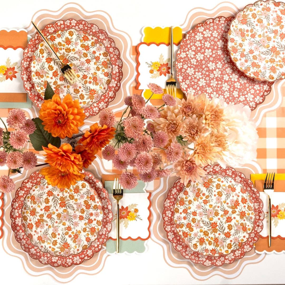 Wide overhead fall tablescape with floral plates, scalloped napkins, mums, and dahlias down the center