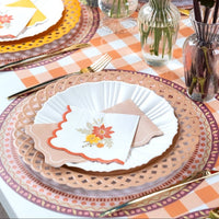 Overhead fall tablescape showing tan napkins layered with floral plates, patterned chargers, and autumn florals.