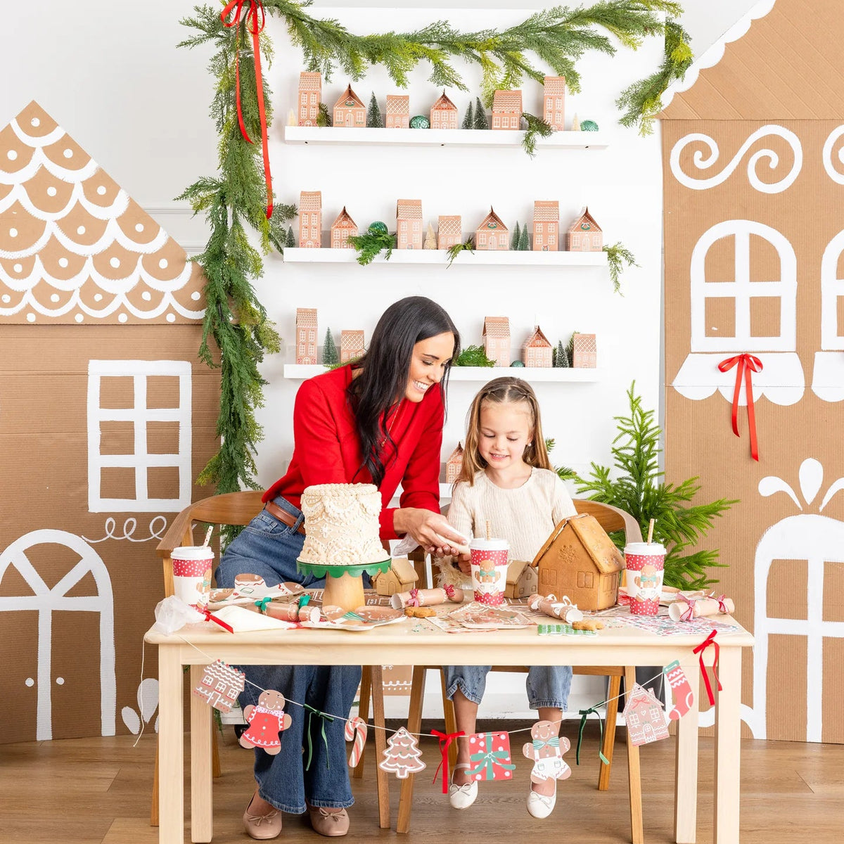 Lifestyle shot of a mother and daughter crafting at a table decorated for a gingerbread Christmas theme party.