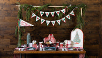 The felt banner hung on a rustic mantel with garland, a Christmas tree, and a styled console.