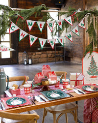 The felt banner strung along a rustic wood table set with plaid tableware and garland.