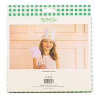 retail packaging for a kids' white felt bunny crown showing a lifestyle photo of a young girl wearing the crown during a spring celebration.