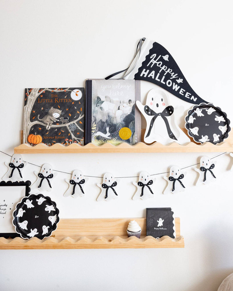 Felt ghost banner draped across a halloween styled floating shelf wall as Halloween decor.