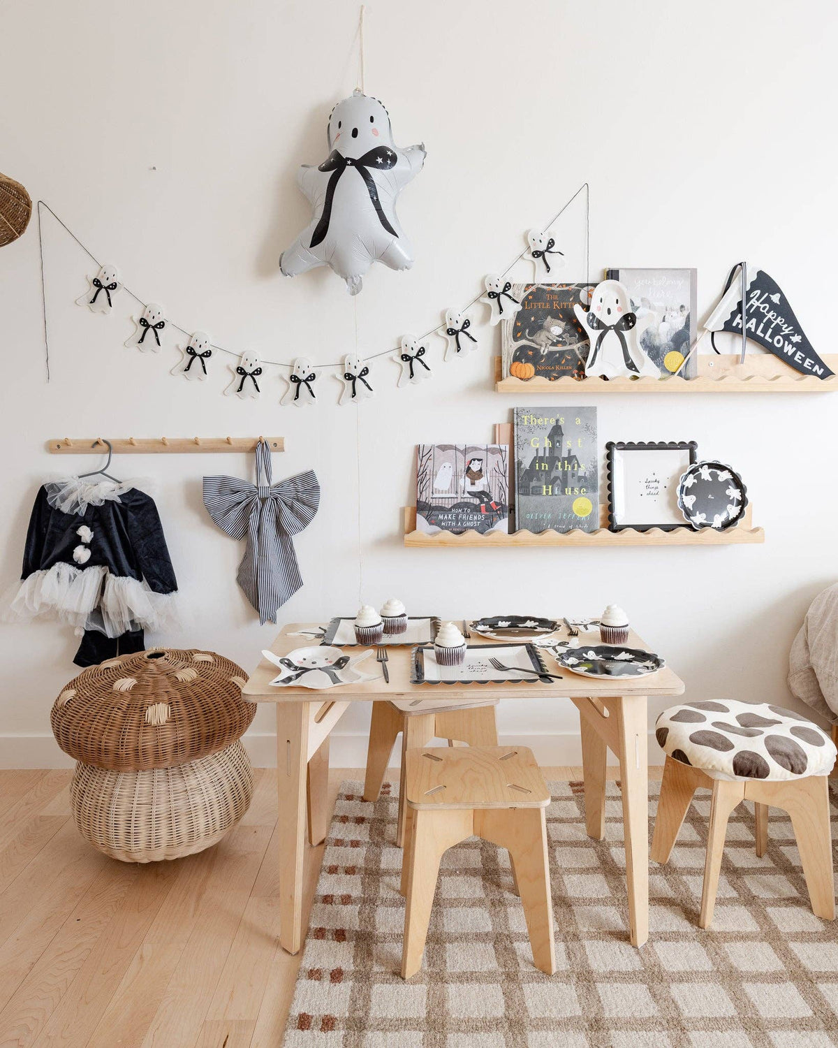 A room full of Halloween themed decorations on a table, chairs, and on a shelf with the ghost felt banner. 