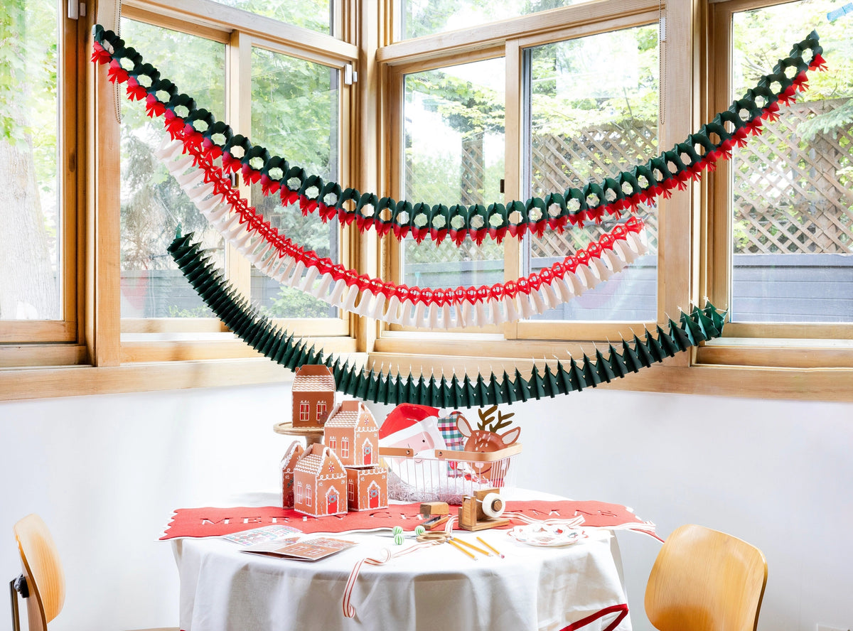 Holiday table set with the felt runner, a green garland, and a red place setting.