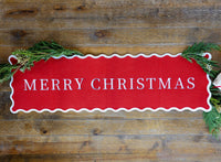 The felt table runner laid on a wood table with greenery.