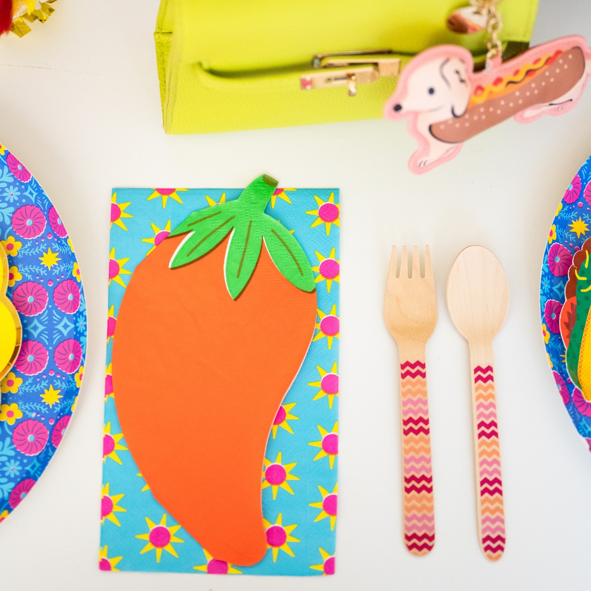 fiesta place setting with turquoise sun napkin chili pepper napkin and wooden utensils
