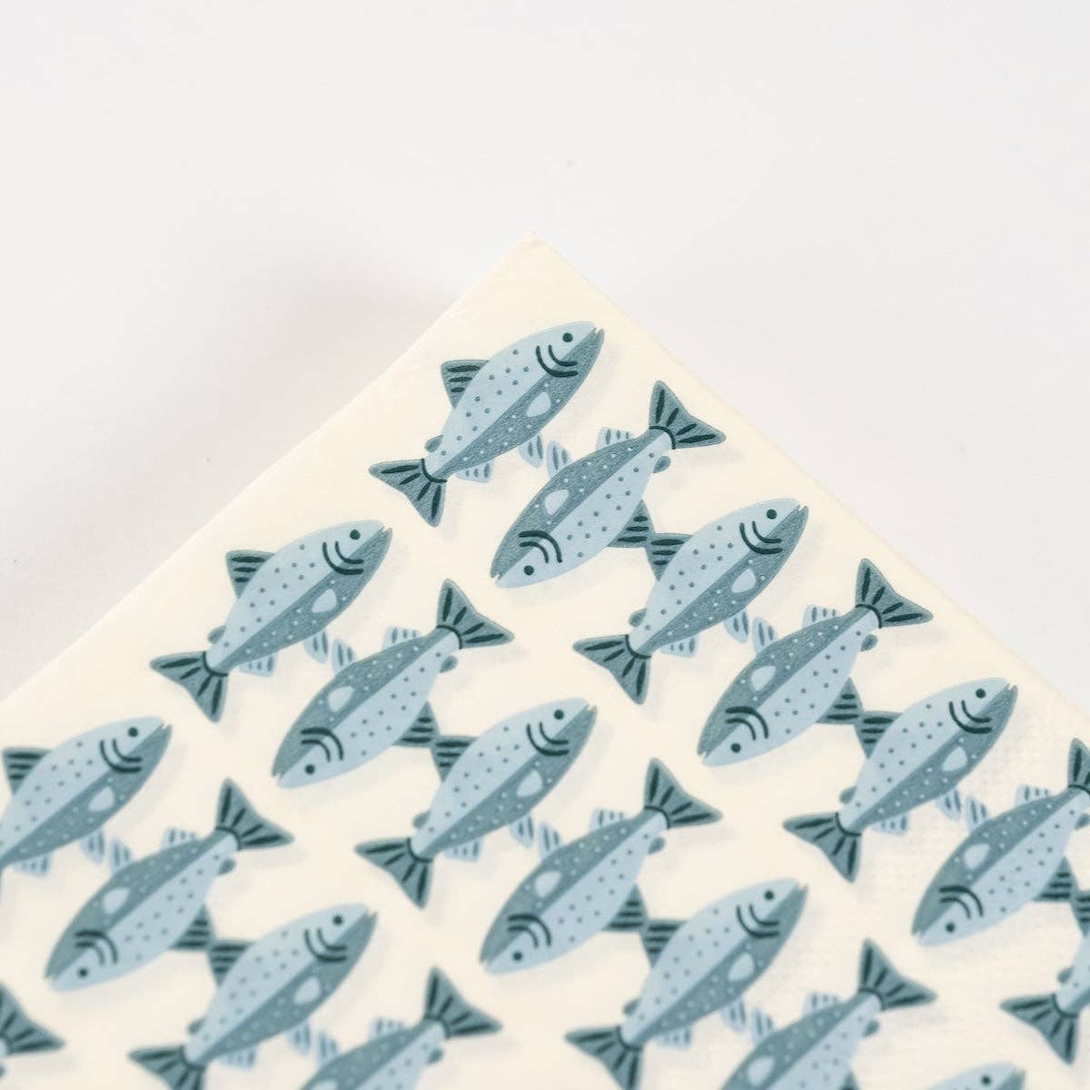 Corner detail of a fish print paper guest towel showing the trout pattern and folded edge.