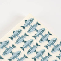 Corner detail of a fish print paper guest towel showing the trout pattern and folded edge.