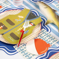 Fish print napkin beside a vest plate and bobber napkin on a wavy blue placemat.
