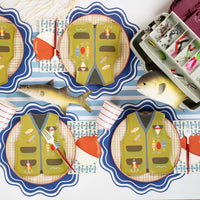 Fishing party tablescape with bobber napkins, vest shaped plates, fish napkins, striped cups, and a tackle box on a striped runner.