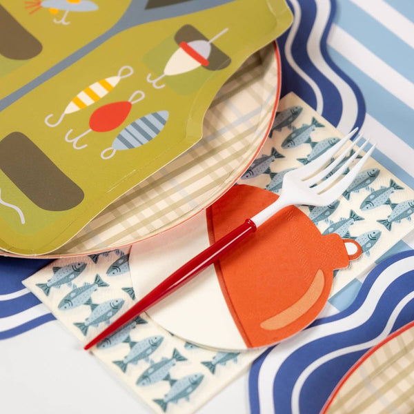 Fishing party place setting with a bobber napkin, vest shaped plate, plaid plate, wavy placemat, striped cup, and tackle box.