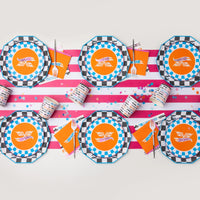 Overhead flat lay showing a table setup featuring the blue checkered plates layered over octagonal plates on a striped runner.