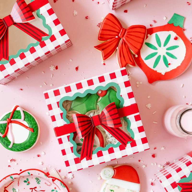 Flat lay of various die-cut party ware items, including the ornament napkins, plates, and gingham cookie boxes.
