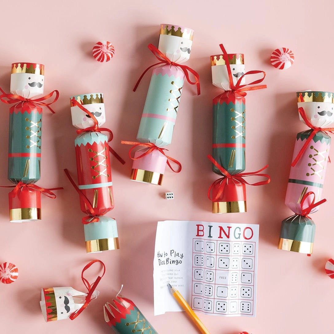 Flat lay of scattered holiday poppers and candy around the included dice bingo lighted Christmas game card.