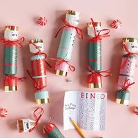 Flat lay of scattered holiday poppers and candy around the included dice bingo lighted Christmas game card.