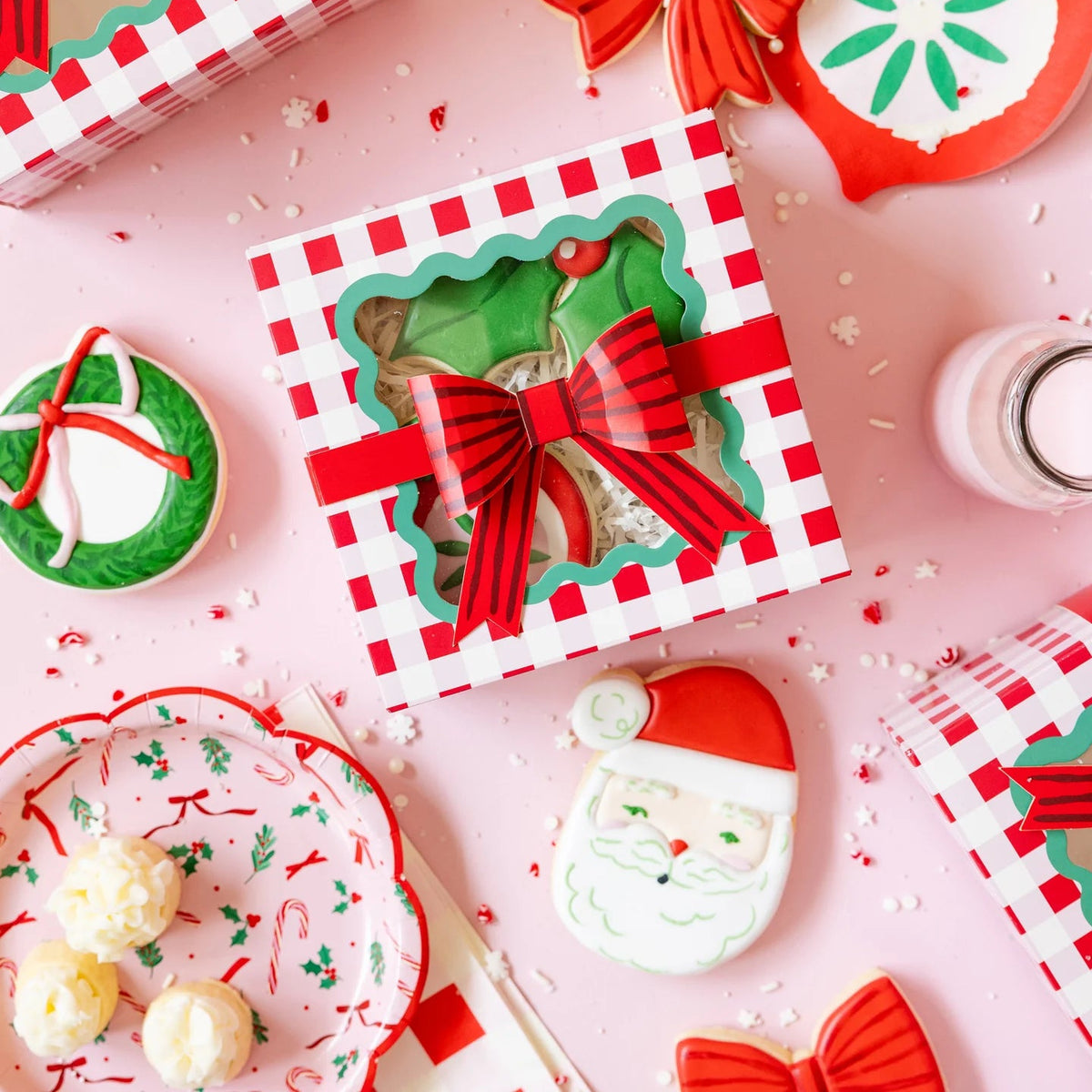 Flat lay showing the paper dessert plates and coordinating gingham cookie boxes on a pink background.