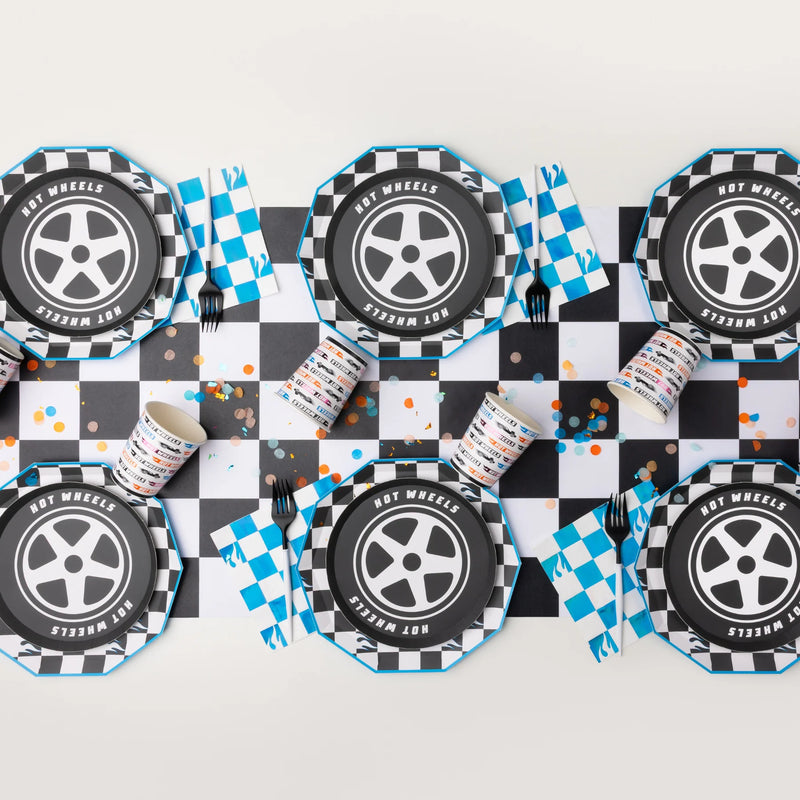 Overhead flat lay showing a large table display with checkered party supplies plates, cups, and race car napkins.