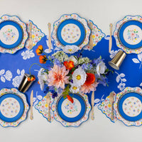 Floral party table setting with matching floral plates and blue accents.
