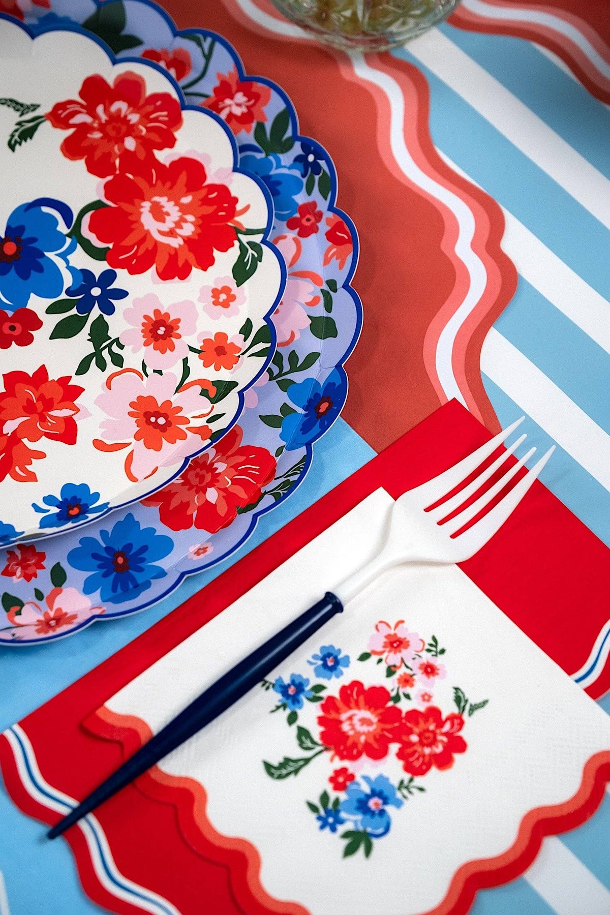 A Floral Patriotic Plate layered with a matching floral napkin and white and blue fork for a Coastal Americana Dinner Party.