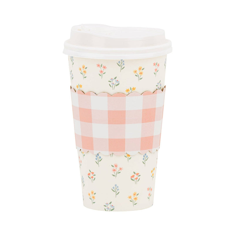 A single 16oz paper coffee cup featuring a wildflower print and a scalloped pink-and-white gingham cardboard heat sleeve on a white background.