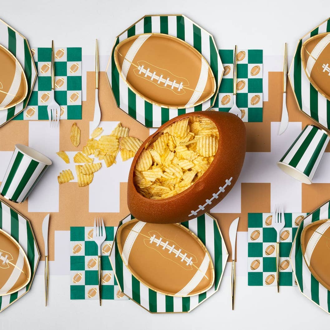 Football themed table with green checker napkins, plates, and game day snacks
